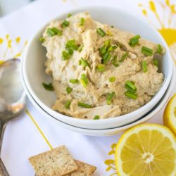 hummus in a white bowl with chopped chives on top