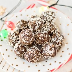 chocolate peppermint energy balls on a plate with christmas lights and candy canes