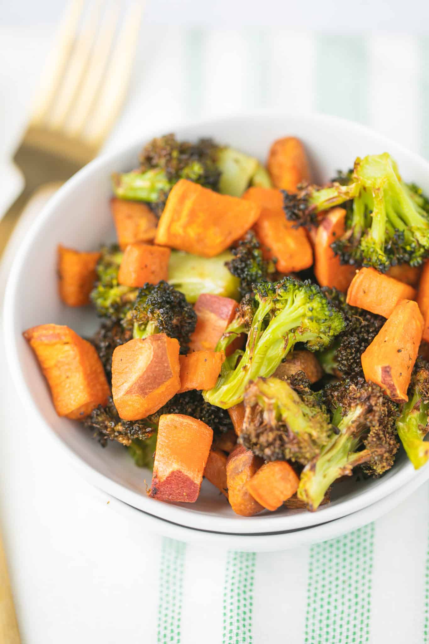 roasted broccoli and sweet potato in a white bowl with a fork
