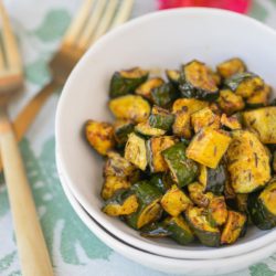 bowl of roasted zucchini with two gold forks