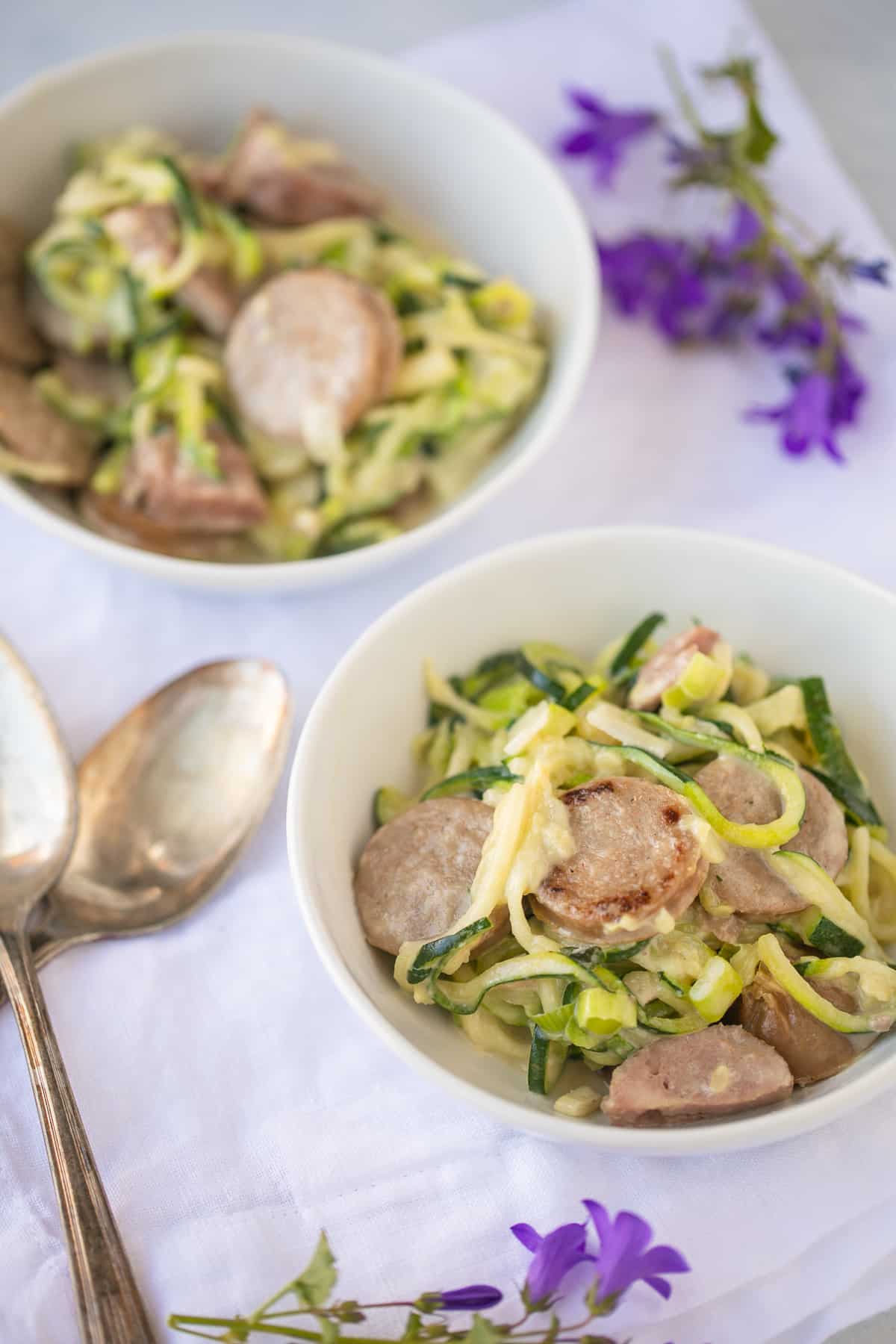 two bowls of zoodles with sausage.