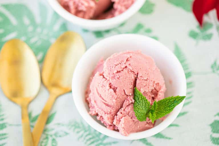 bowl of pink ice cream with mint on top.