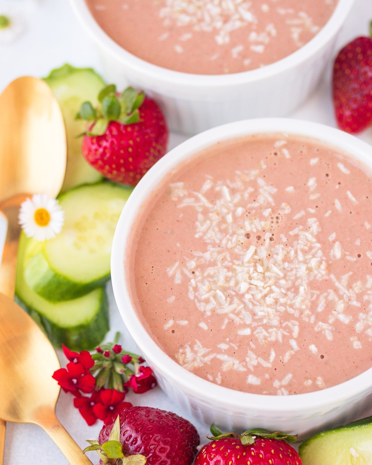 two bowls of strawberry bisque soup with shredded coconut on top.