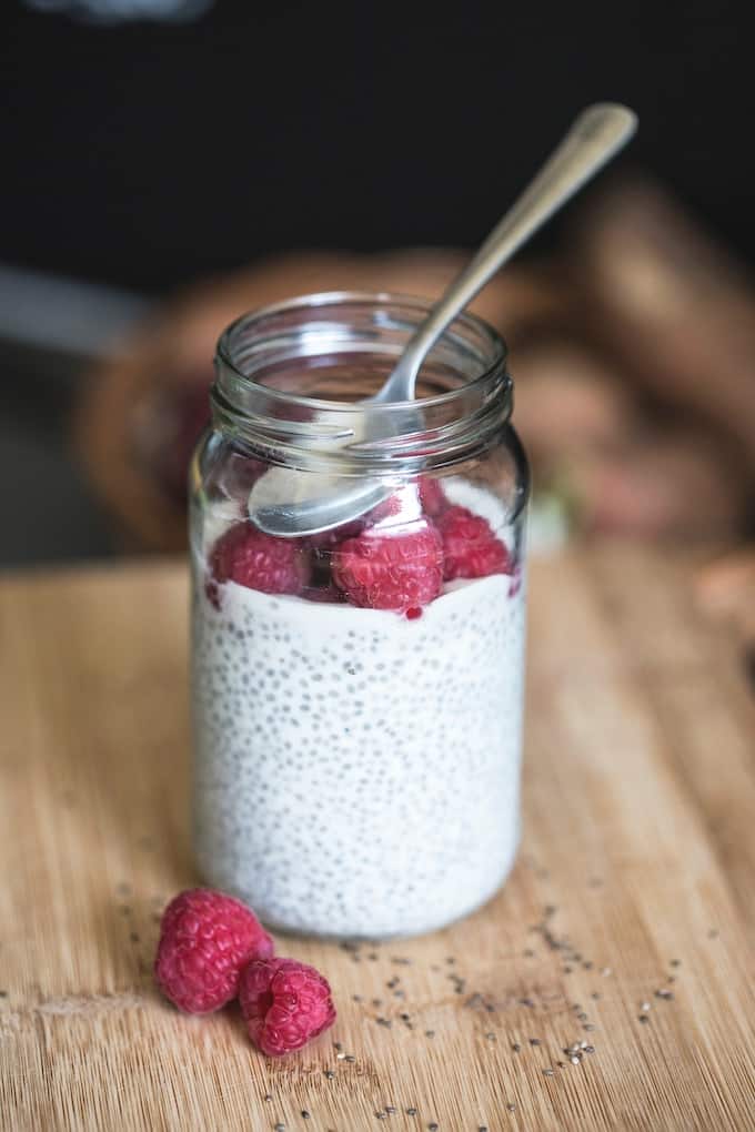 chia pudding in a jar with fresh raspberries on top.