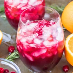 two glasses of pomegranate cranberry mocktail served with fresh orange slices