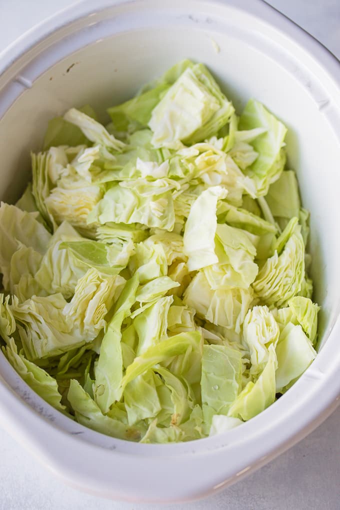 chopped cabbage in crockpot ready to be cooked