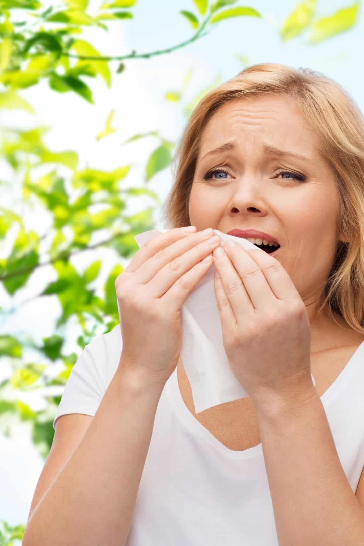 woman outside sneezing into a tissue