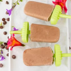 three vegan popsicles on a tray with chocolate chips