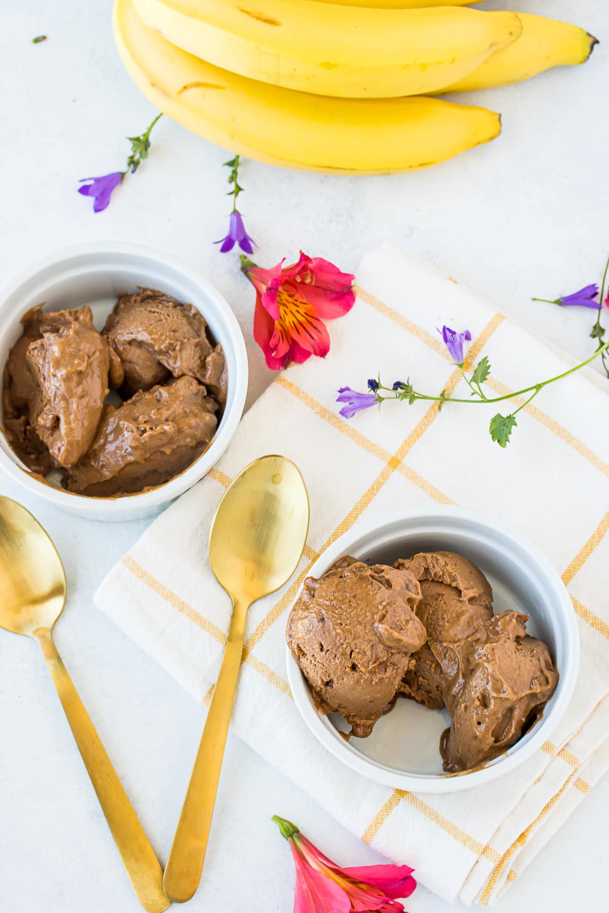 bowls of vegan ice cream with a bunch of bananas on a table