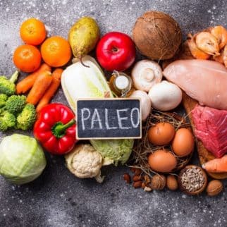 fruits and vegetables and meats on a countertop with a sign that says paleo