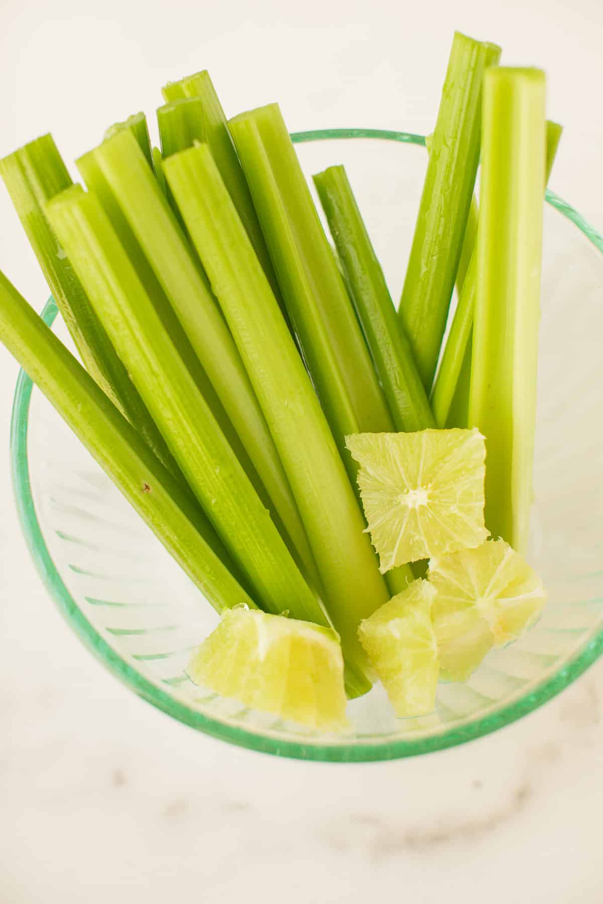 celery stalks and peeled limes in a bowl.