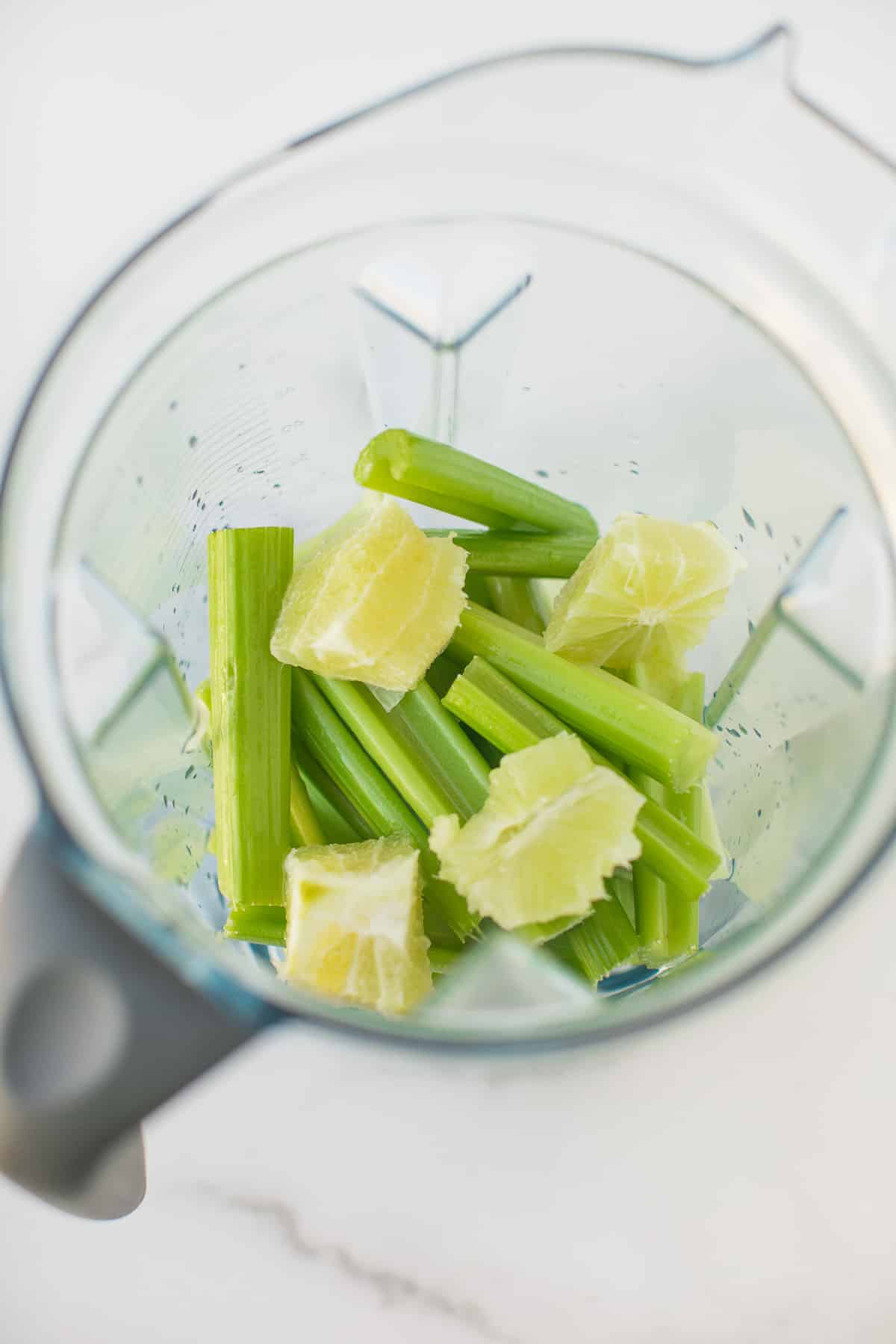 tiges de céleri et citrons verts pelés dans le socle d'un vitamix