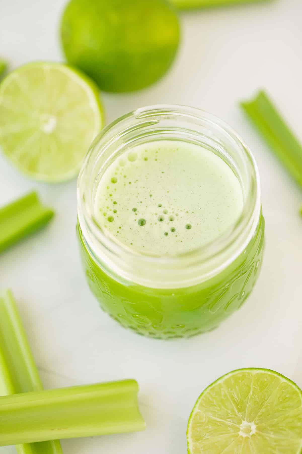 celery juice in a serving glass with white foam on top