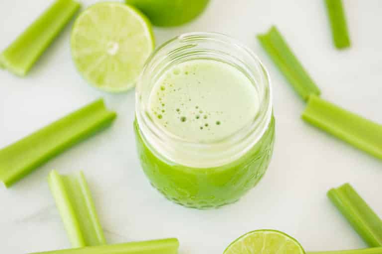 jar of fresh celery juice on a table with celery stalks.