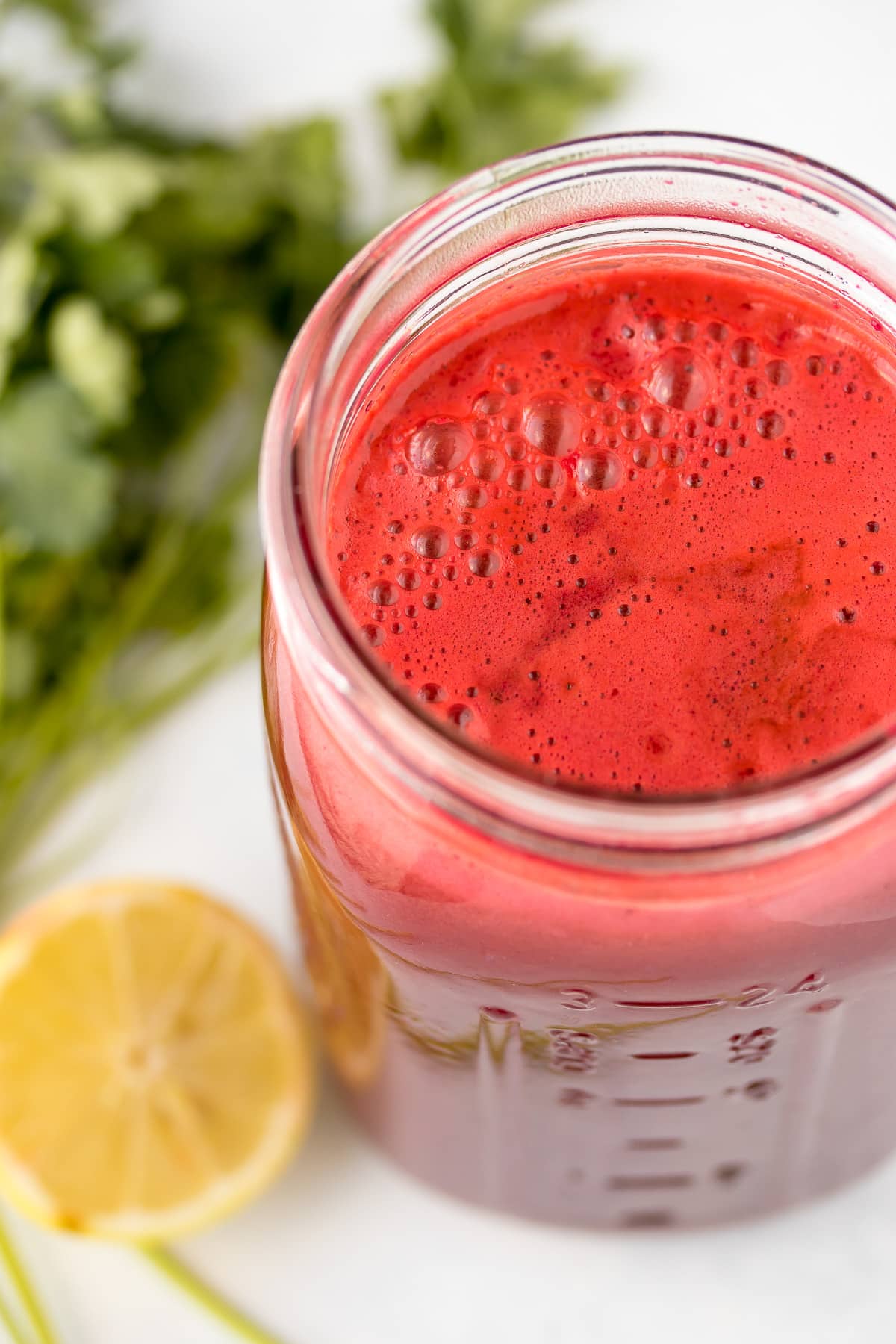 jar of fresh beetroot juice with a sliced lemon beside it