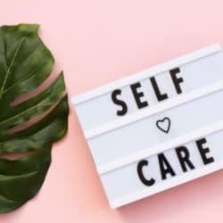 sign that says self care on it next to a plant