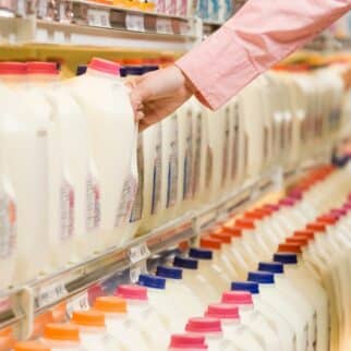 woman grabbing carton of milk at store.