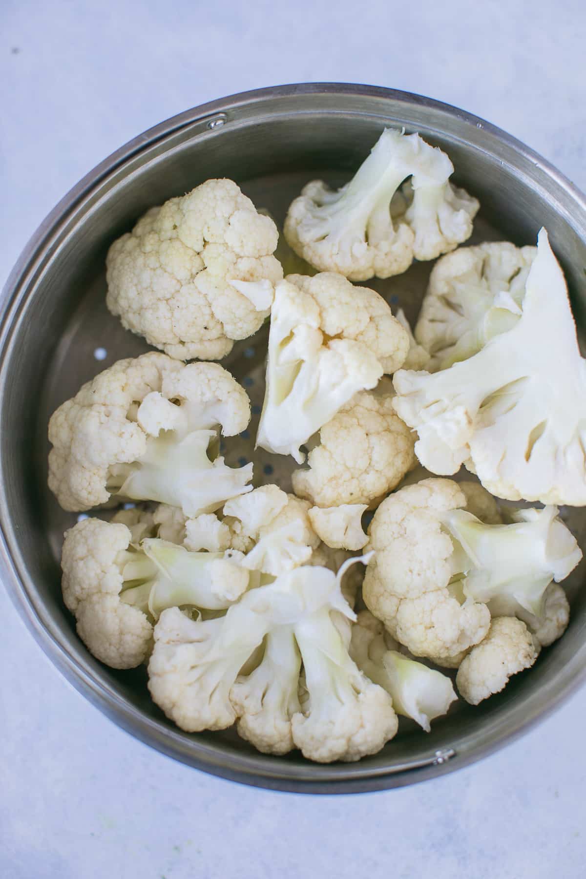 cauliflower florets in a steamer basket ready to be steamed