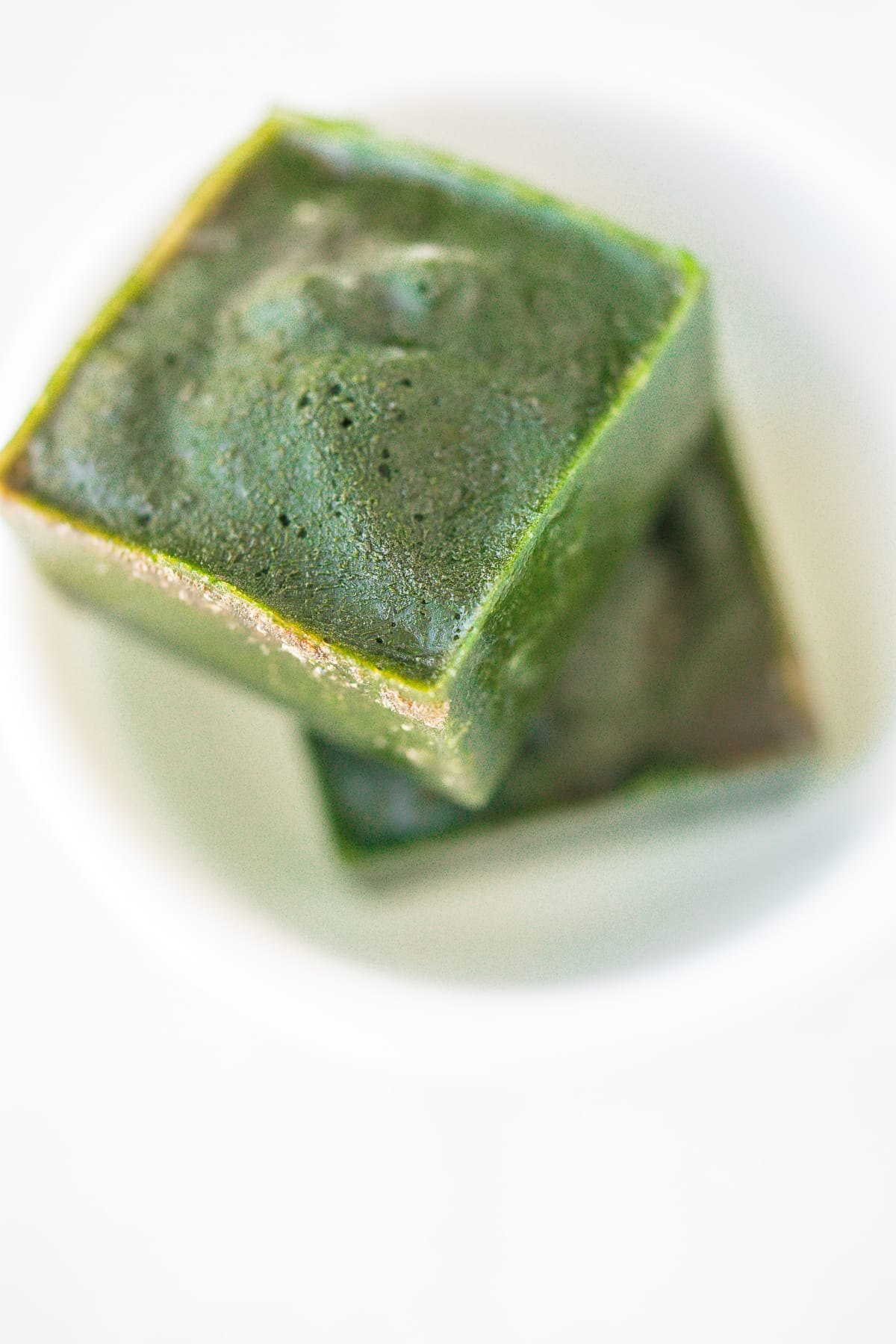 two spinach ice cubes in a white bowl