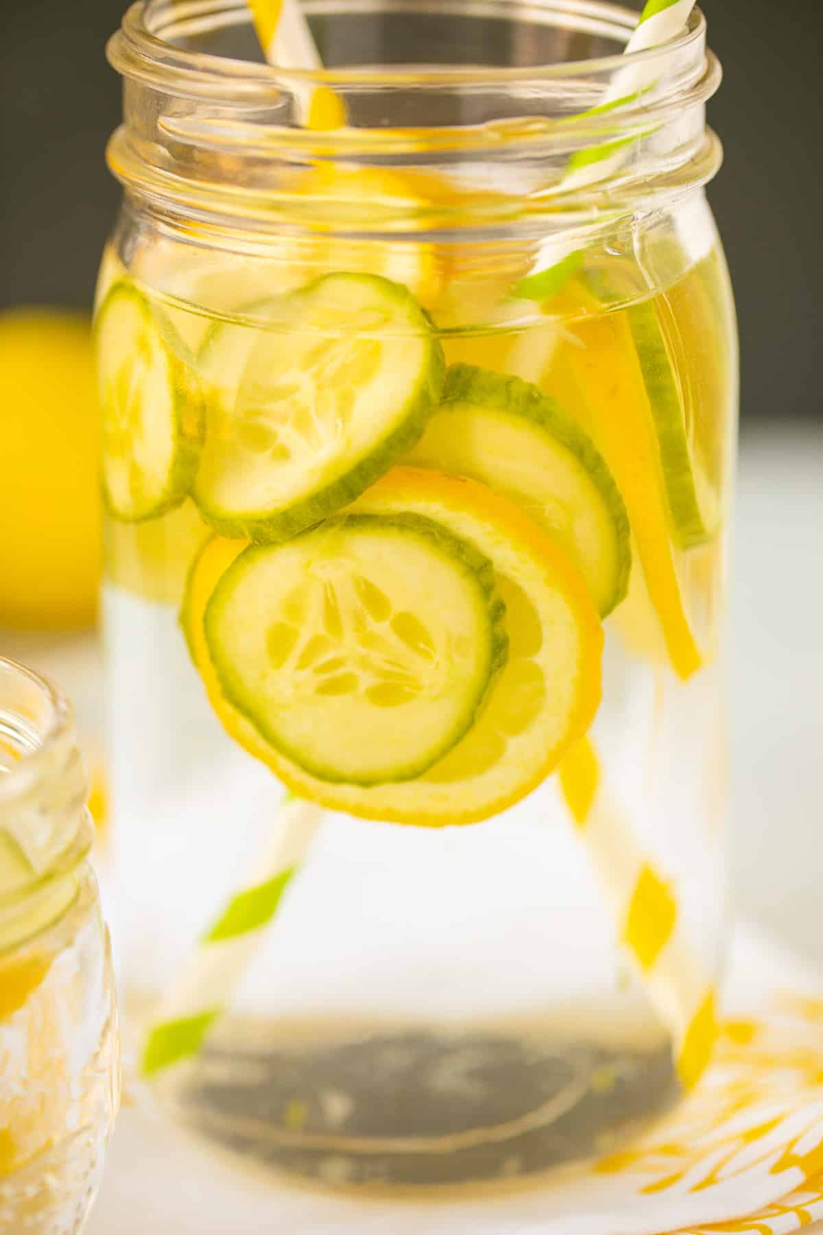 mason jar with cucumber and lemon water and straws