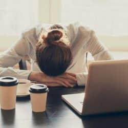 tired woman at laptop with coffee