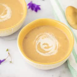 two bowls of zucchini soup with two gold spoons
