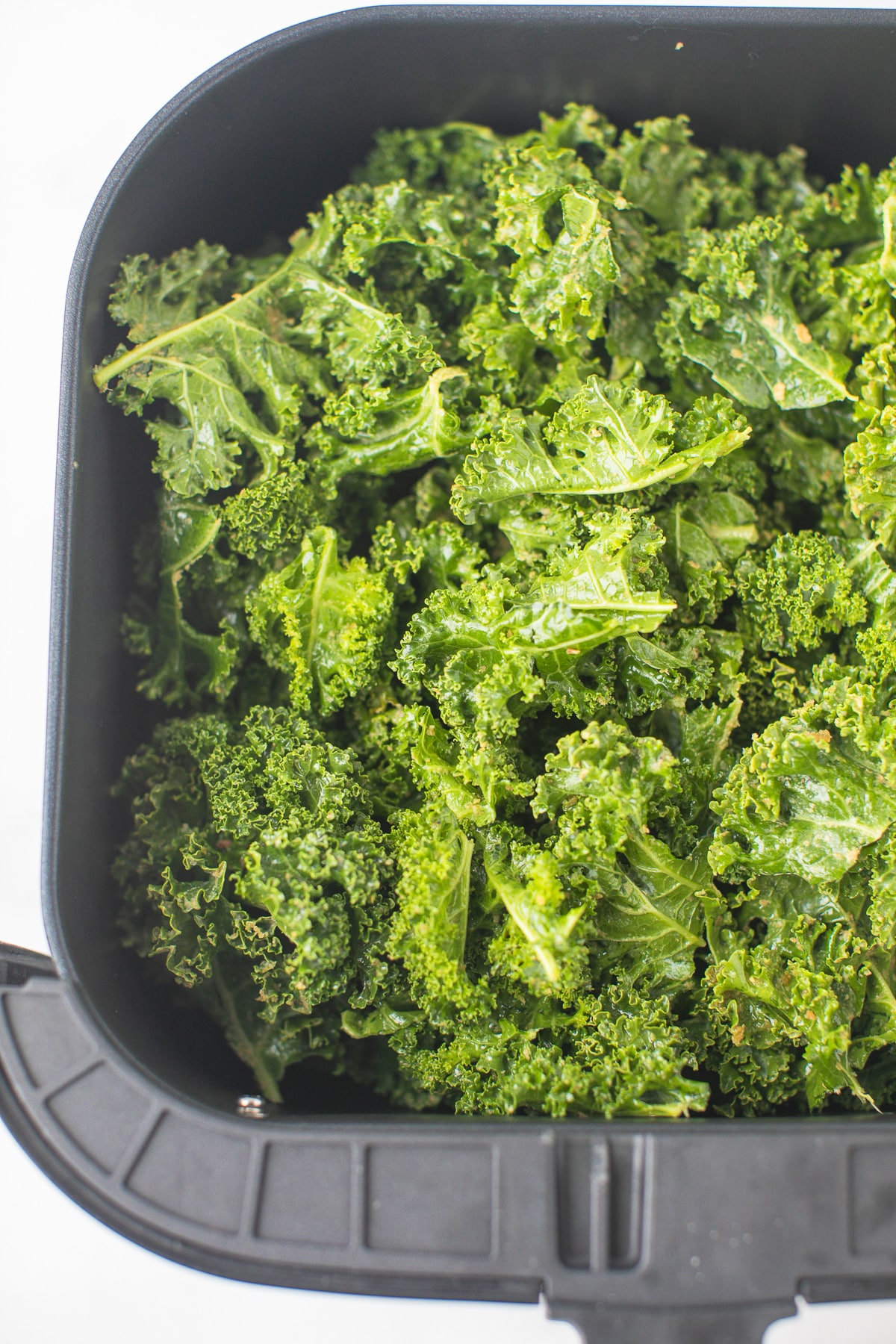 kale chips in the basket of an air fryer ready to be cooked