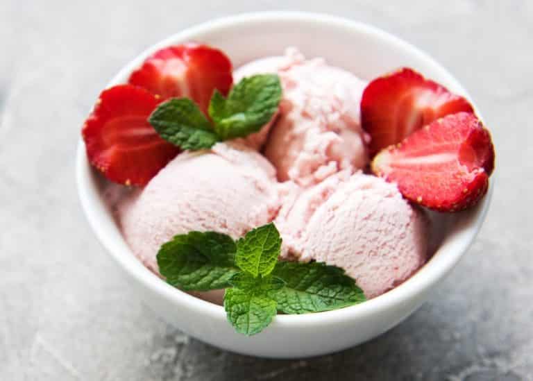 bowl of pink strawberry ice cream with fresh strawberries.