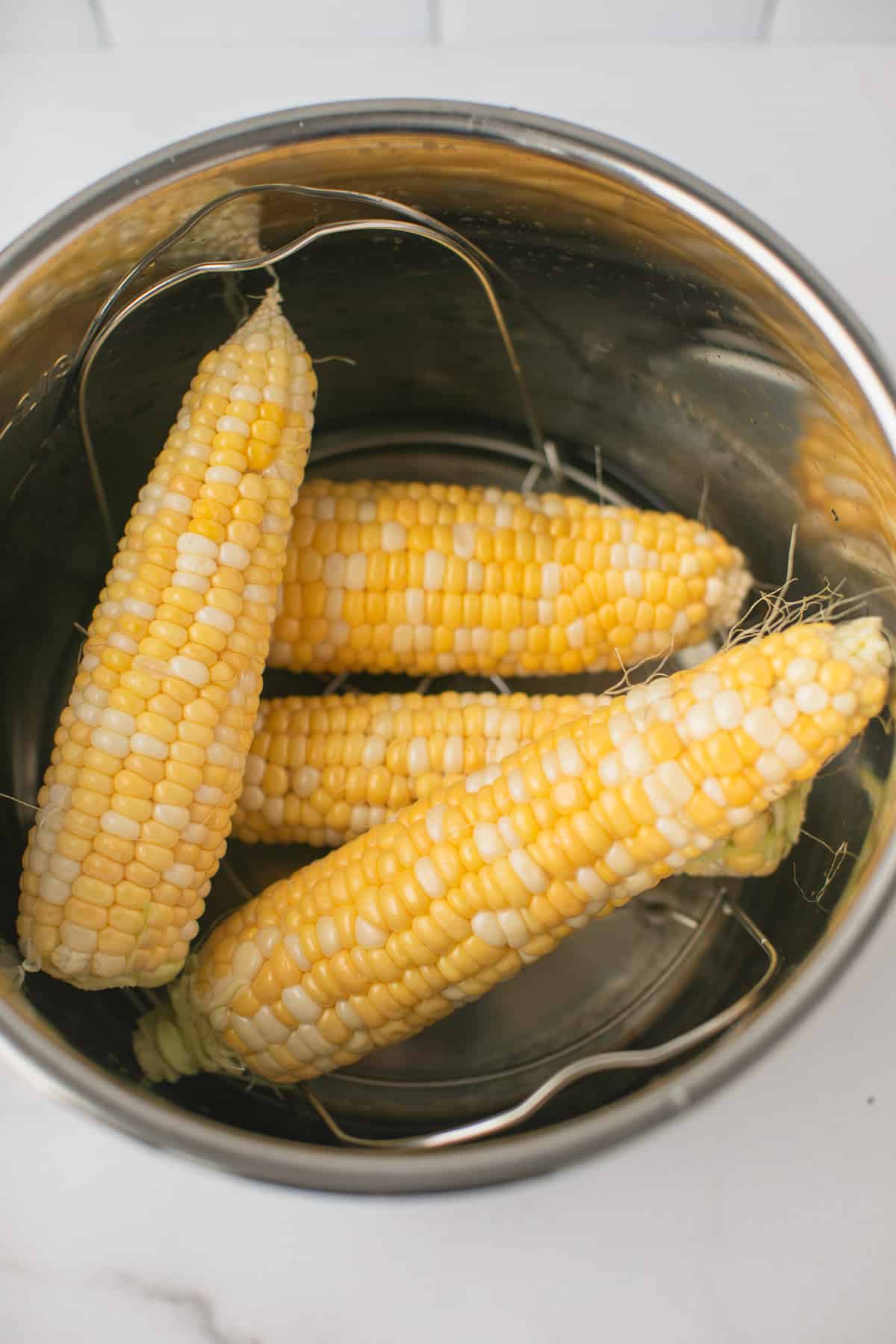 four pieces of corn on the cob inside an instant pot pressure cooker