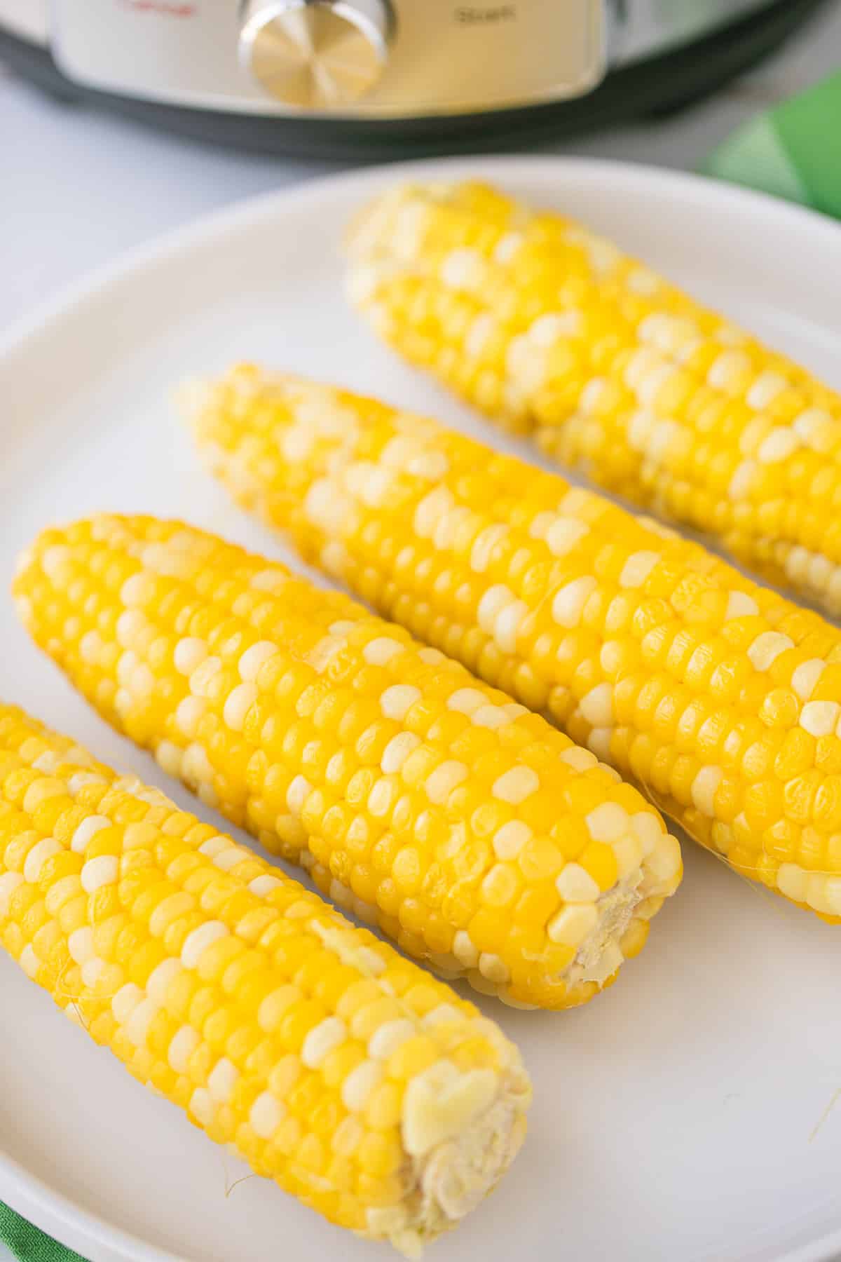 four pieces of cooked corn on the cob on a serving plate