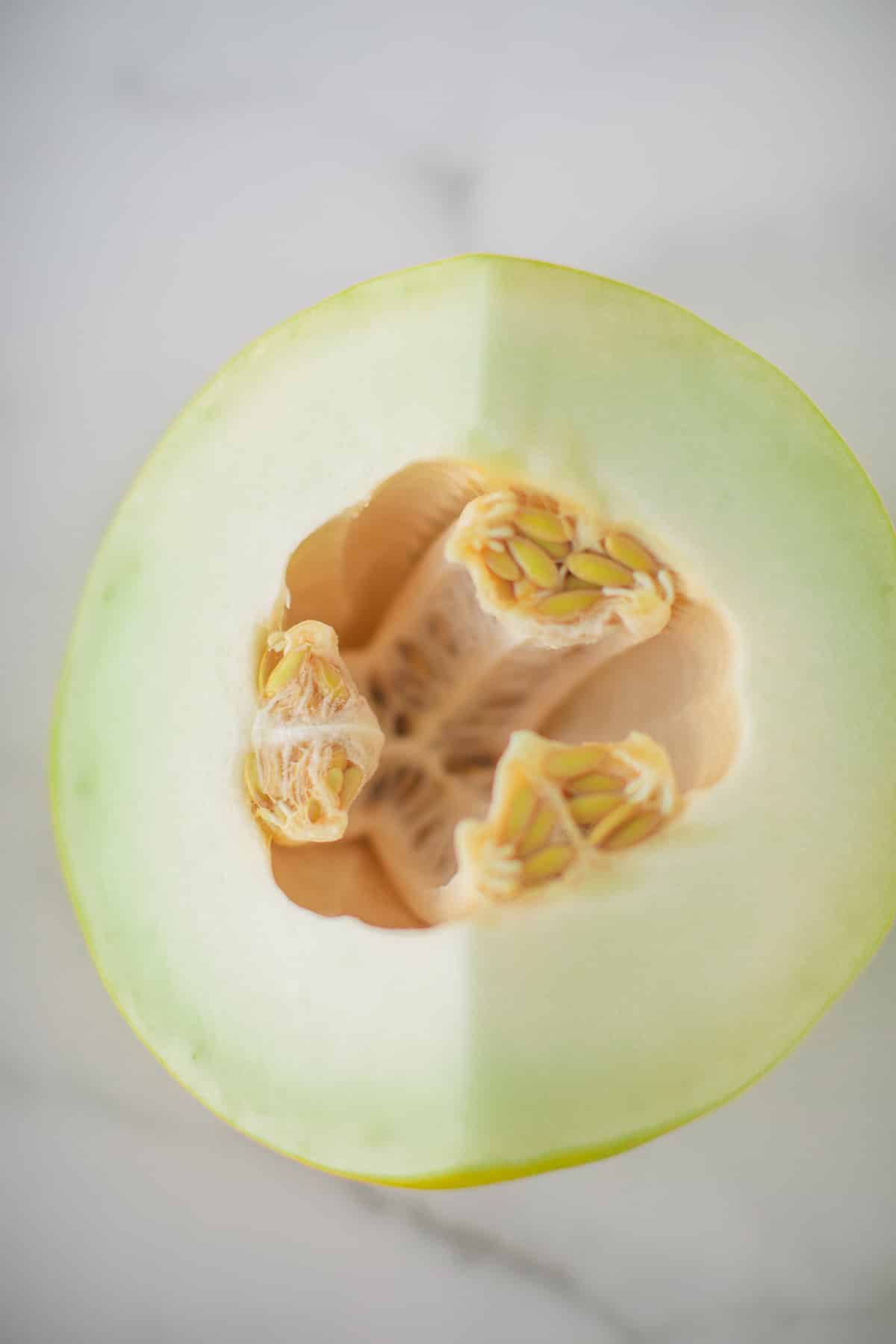 picture of honeydew melon cut in half with the seeds inside