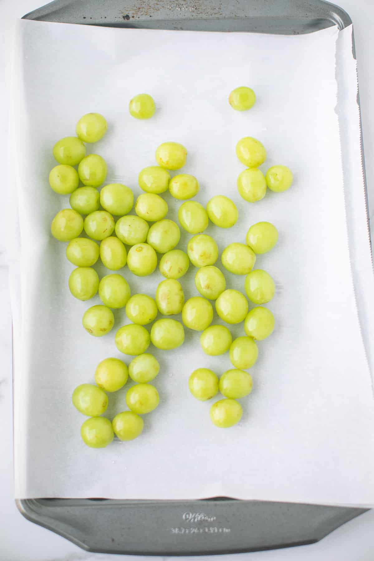 washed grapes on a baking sheet lined with parchment paper.