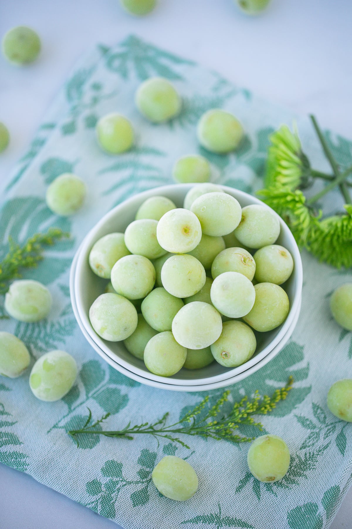 bowl of green frozen grapes on a countertop.