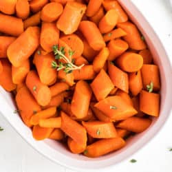 bowl with cooked carrots topped with fresh thyme