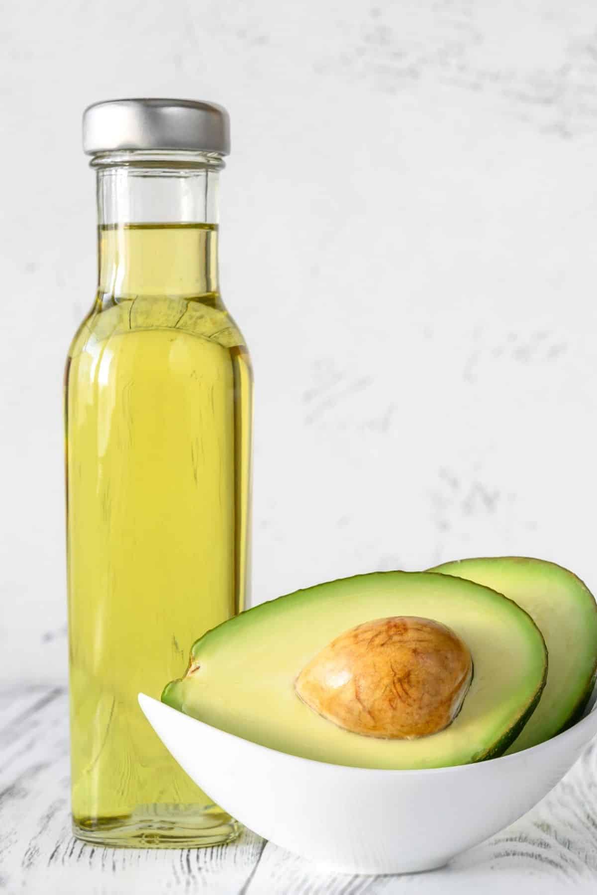 jar of avocado oil with a sliced fresh avocado next to it