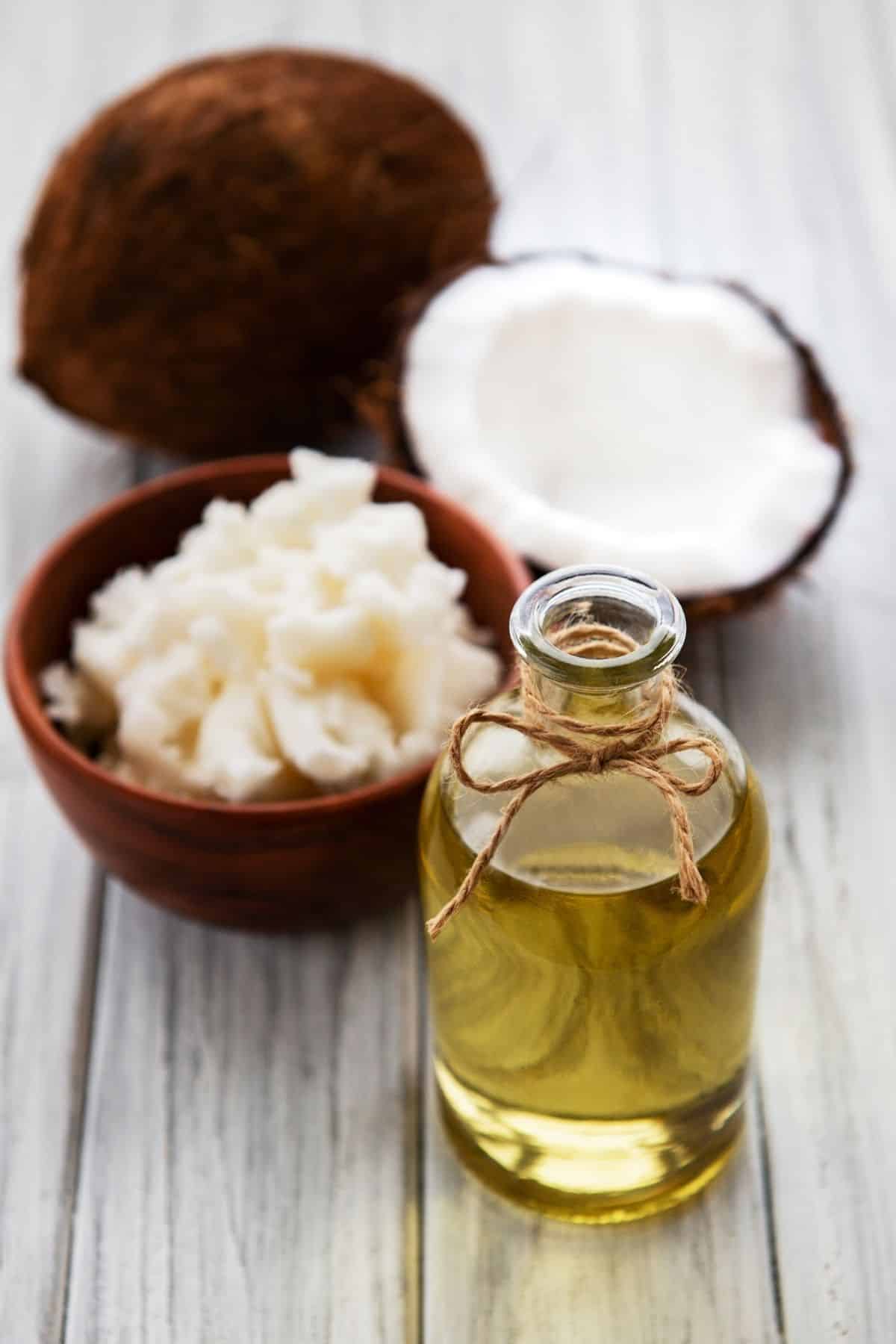 jar of melted coconut oil on a table with some fresh coconut meat