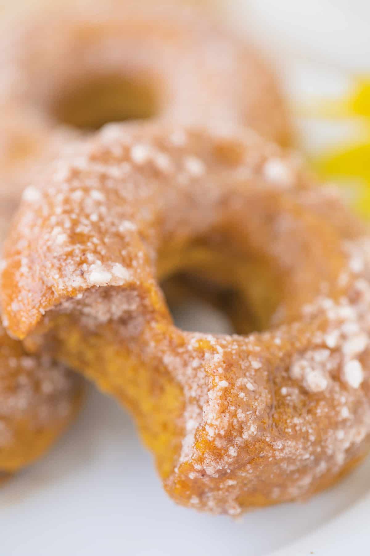 up close picture of a pumpkin baked donut with a bite taken out of it