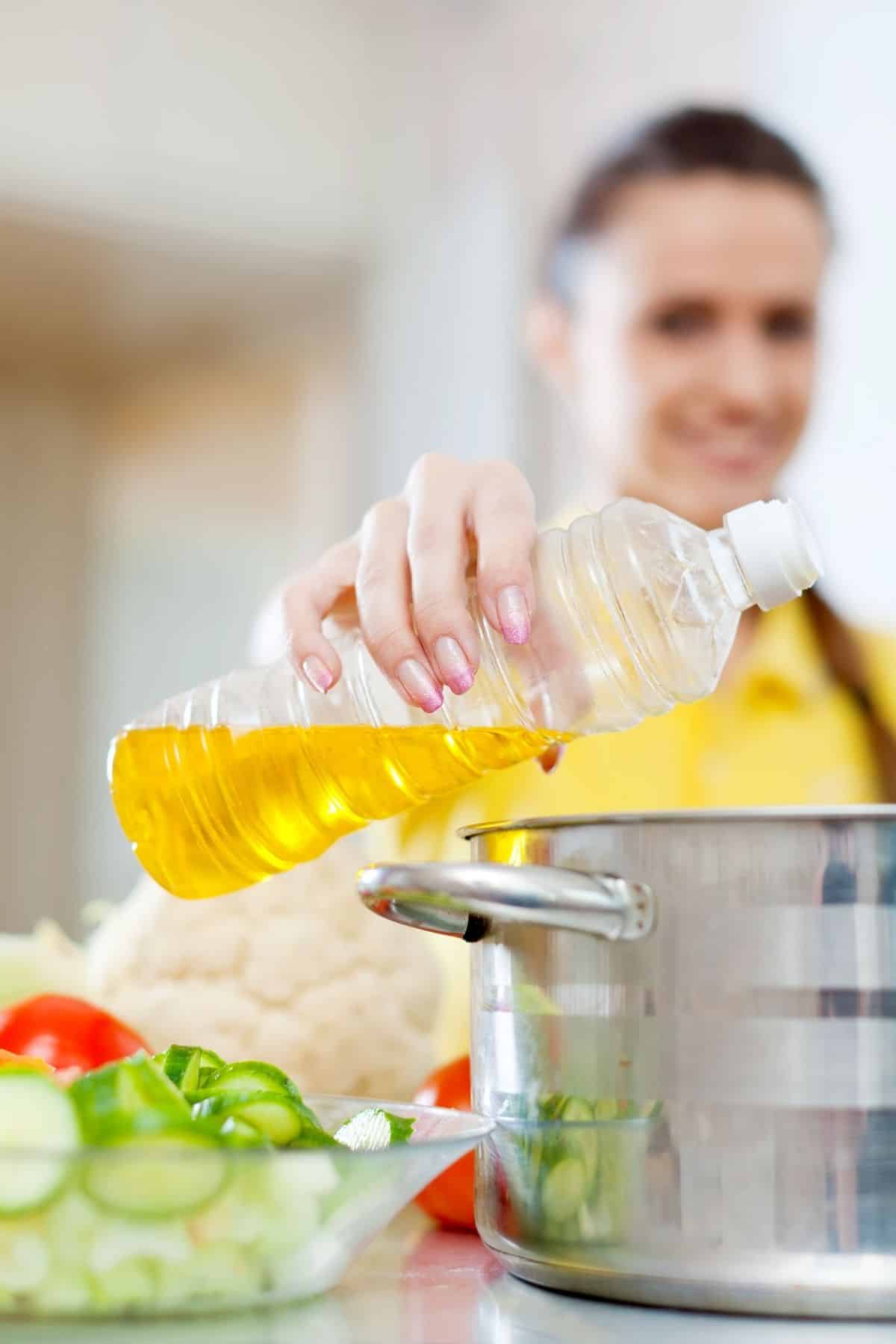 woman pouring oil into a pot for cooking