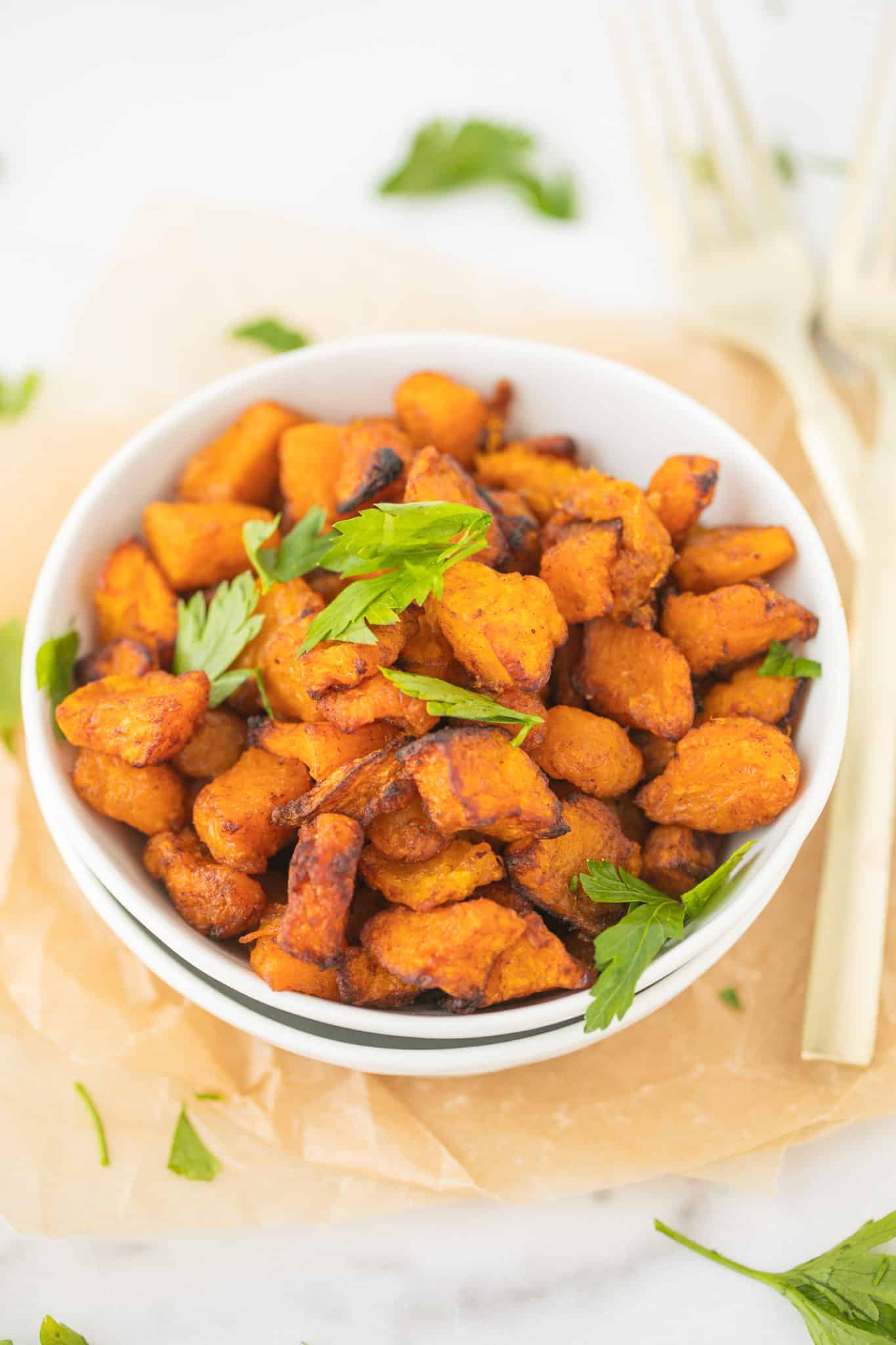 bowl of air fried butternut squash with fresh parsley on top