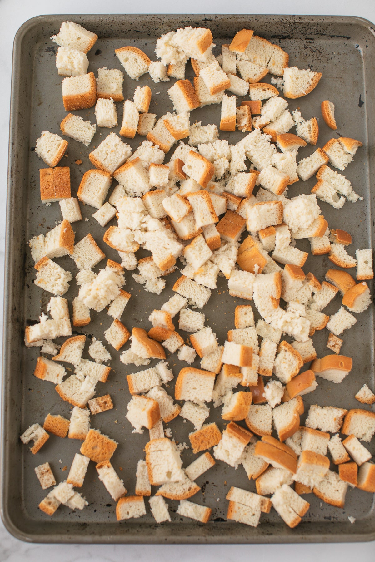 bread cubes on a baking sheet ready to be baked