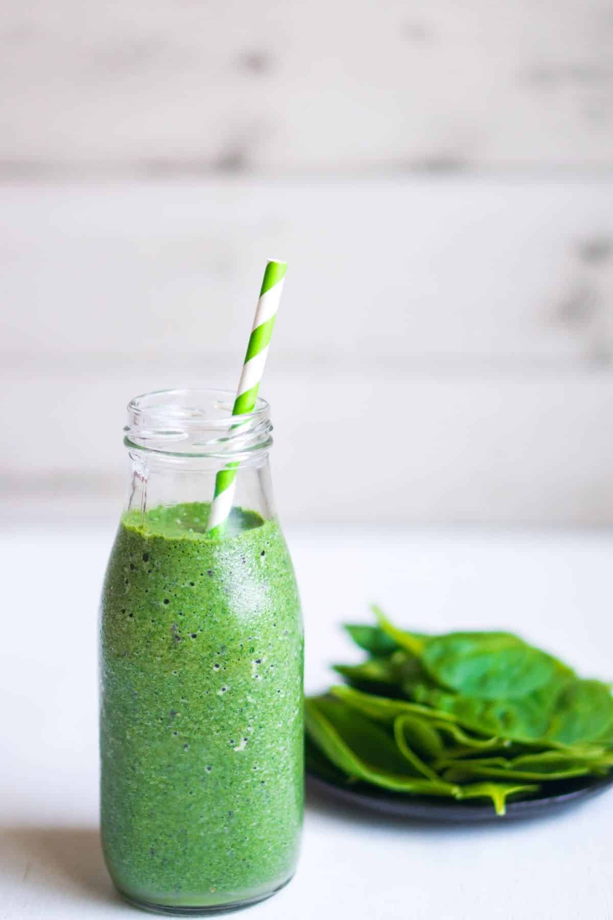 jar of bright green blended smoothie with fresh spinach.