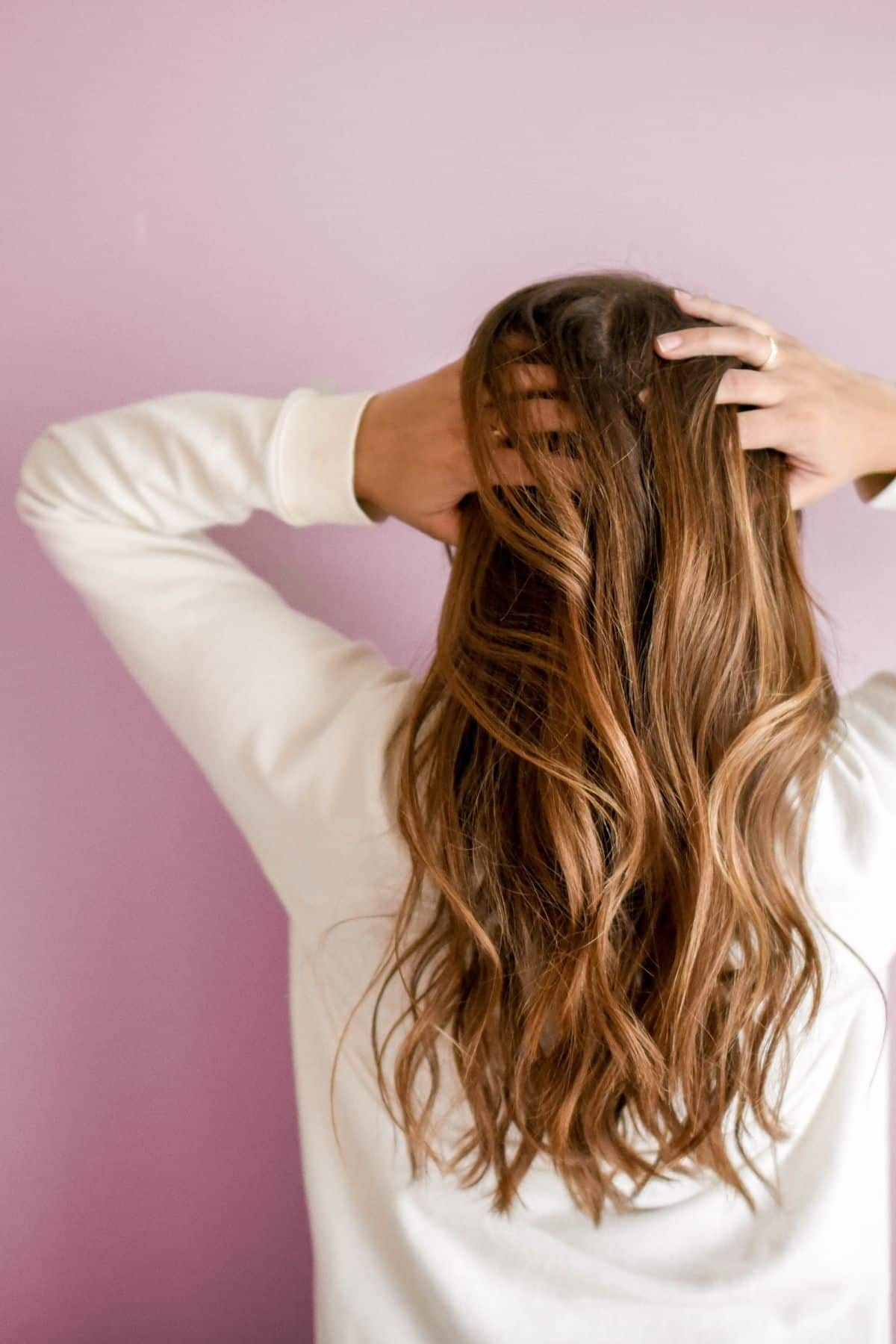 woman with long brown hair holding her head