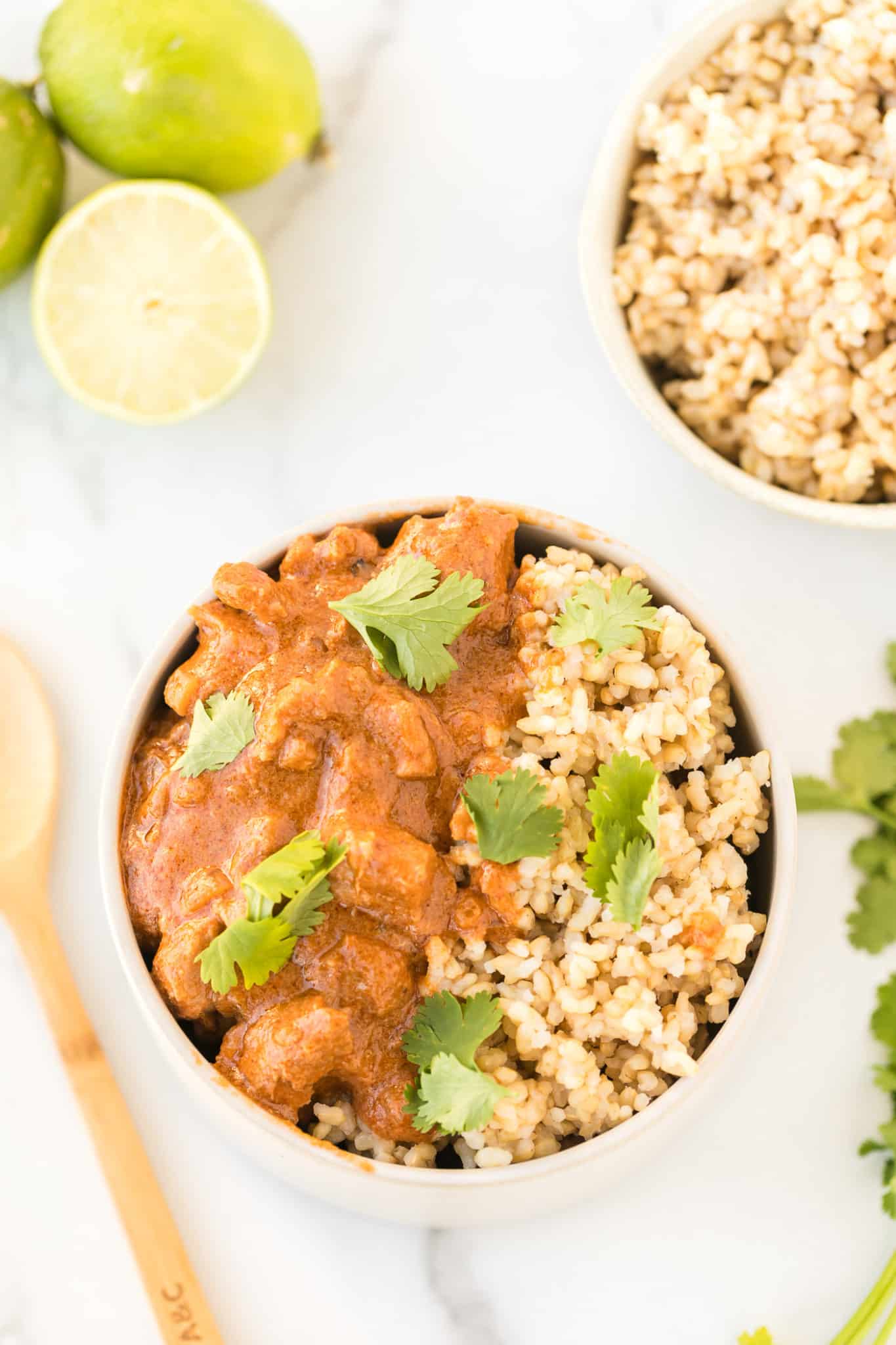 instant pot peanut chicken served in a bowl with brown rice and topped with cilantro leaves.
