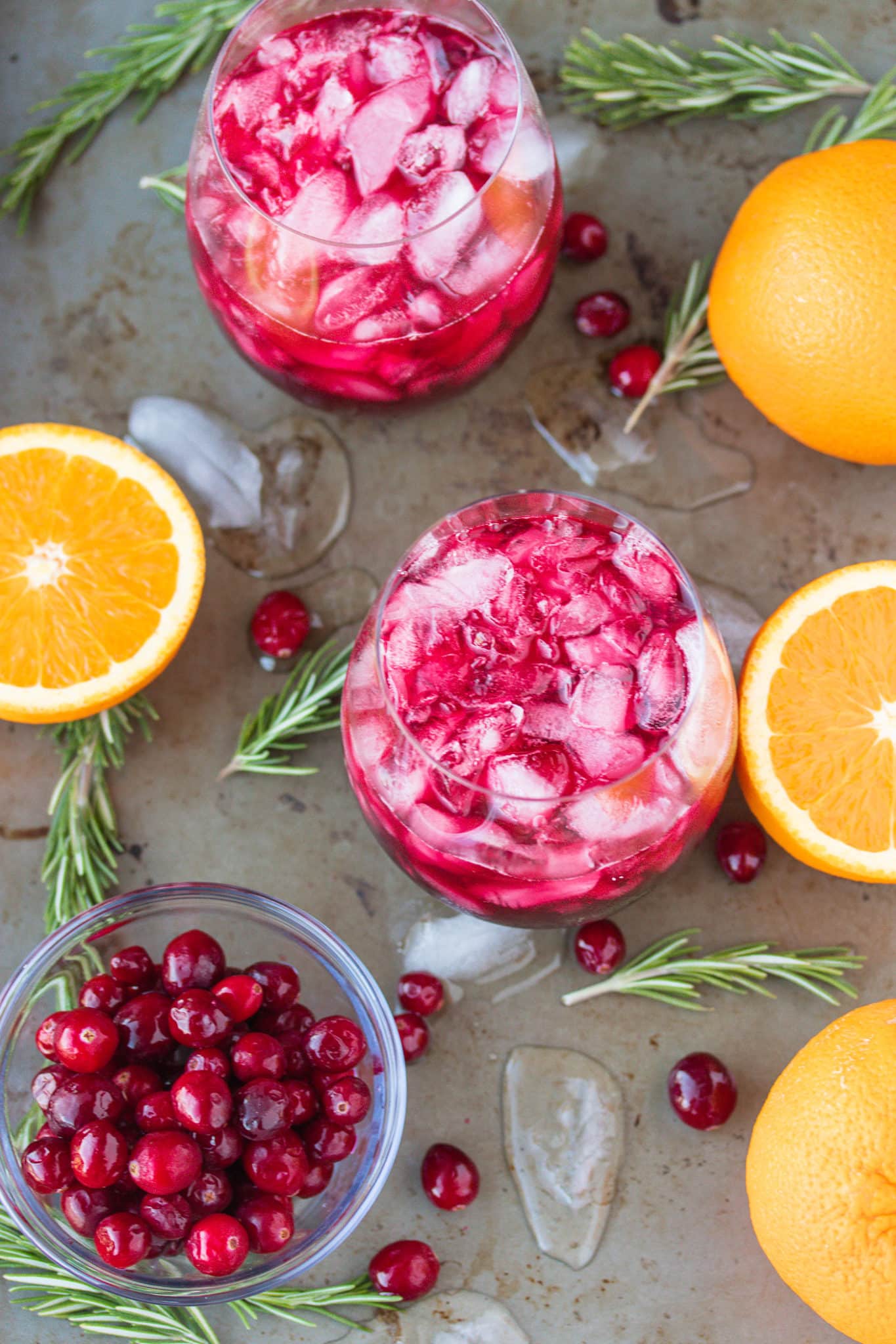 pomegranate cranberry mocktail served with crushed ice on a tray with fresh rosemary sprigs 