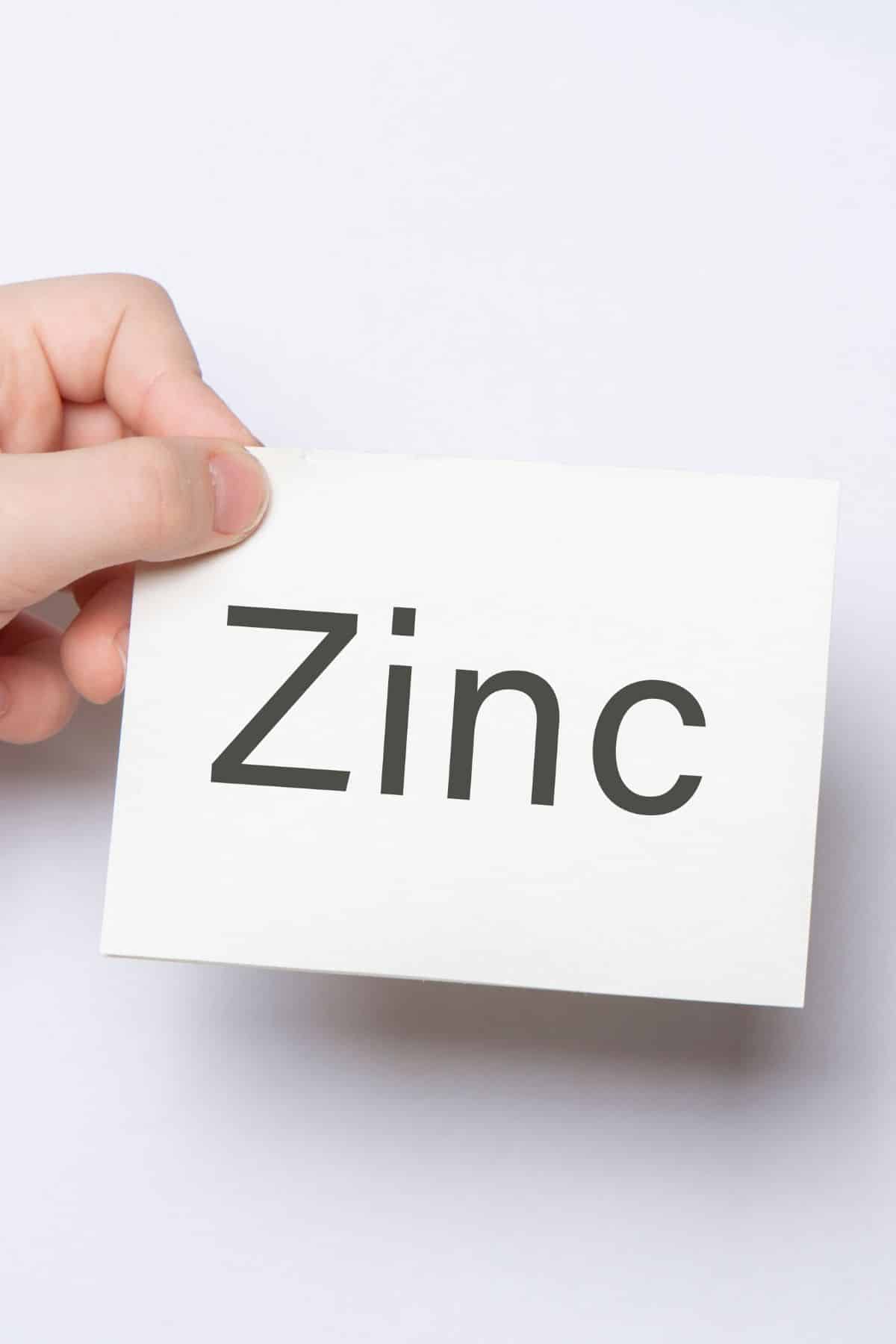 hand holding a note that says zinc on it.