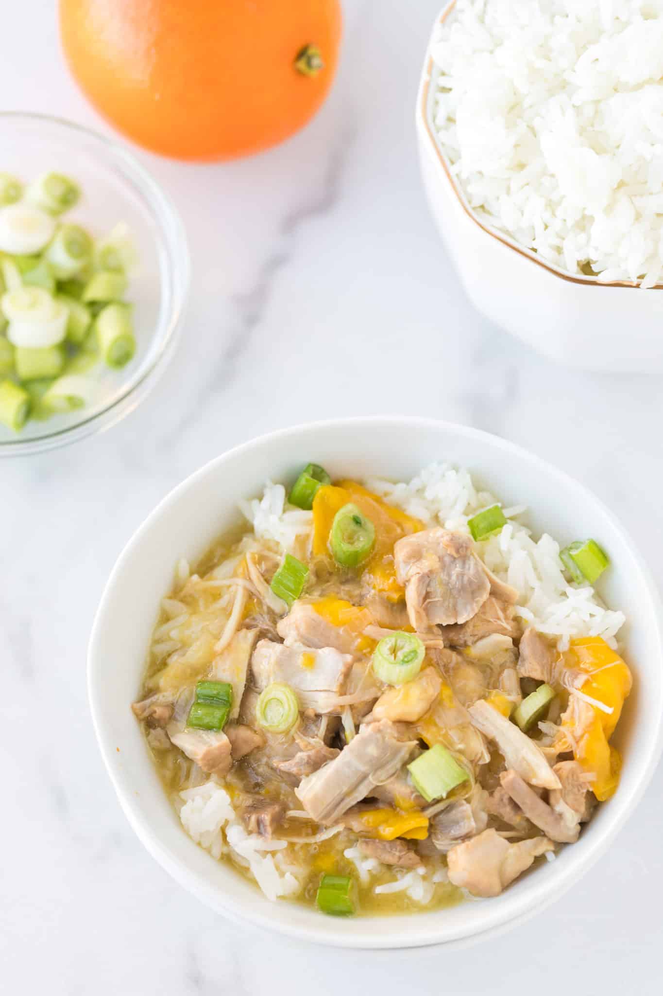 bowl of instant pot orange chicken served with steamed white rice and sliced green onions