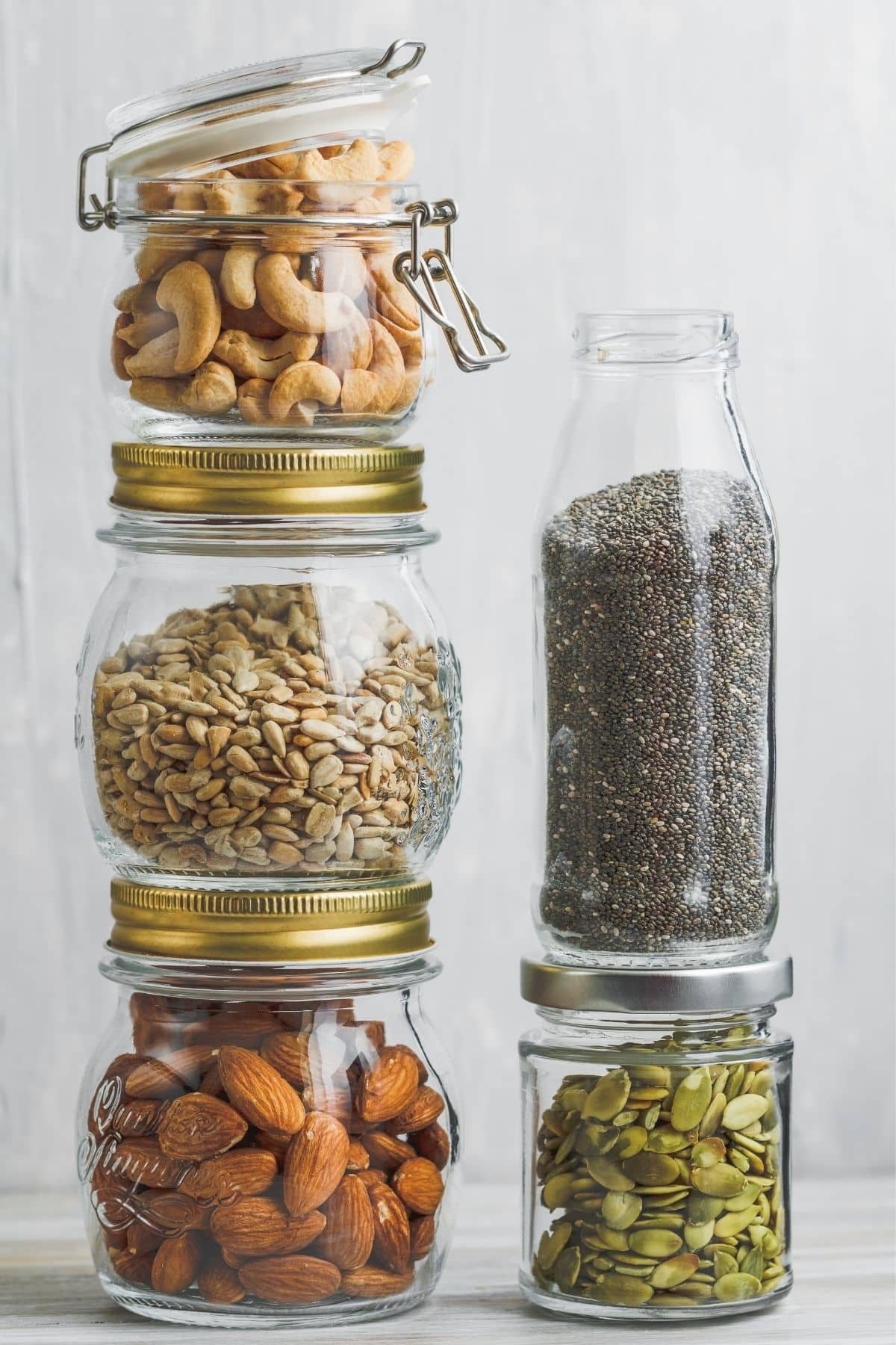 nuts and seeds in jars stacked on a table.