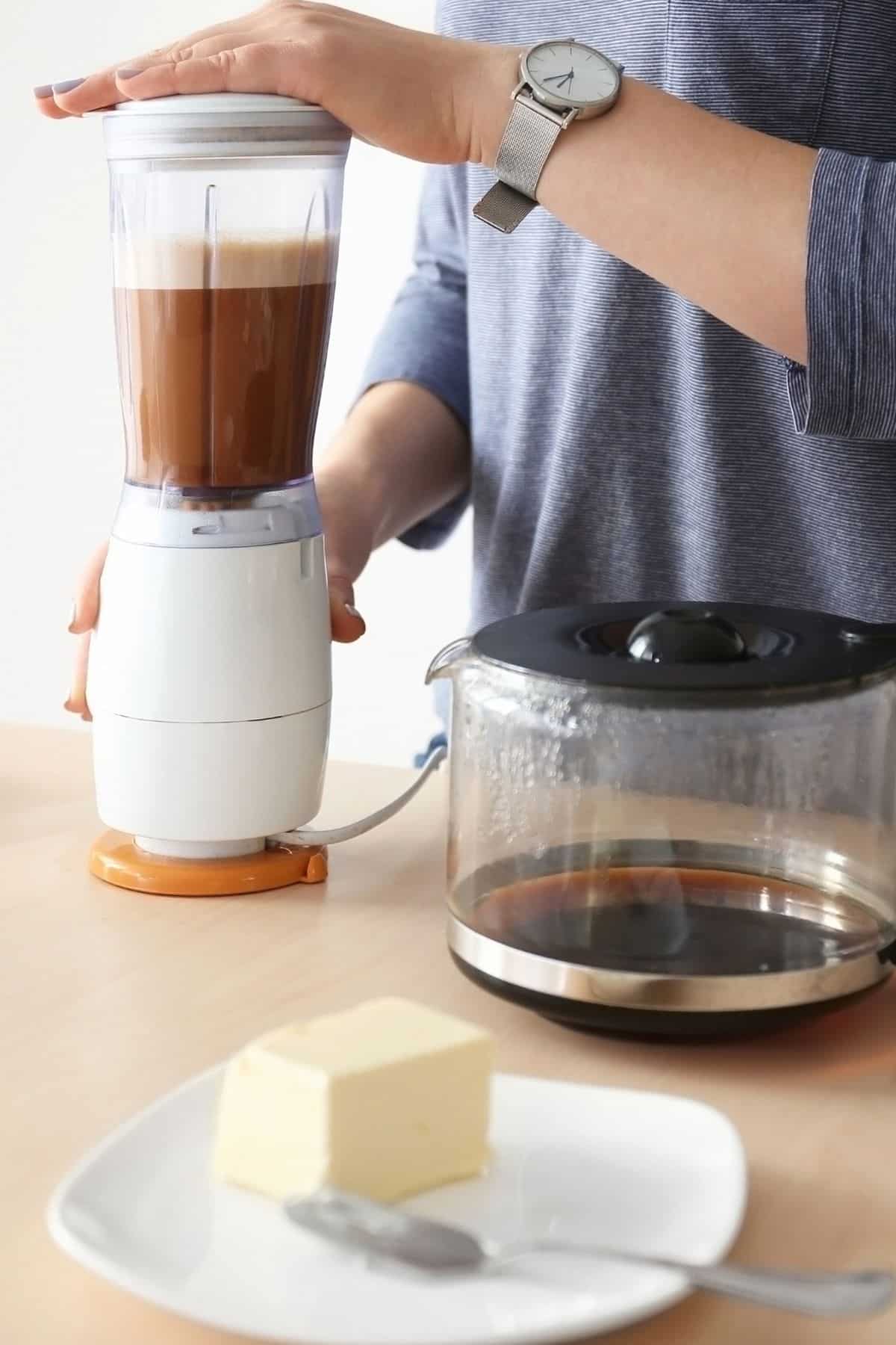 woman making butter coffee in a kitchen using a blender