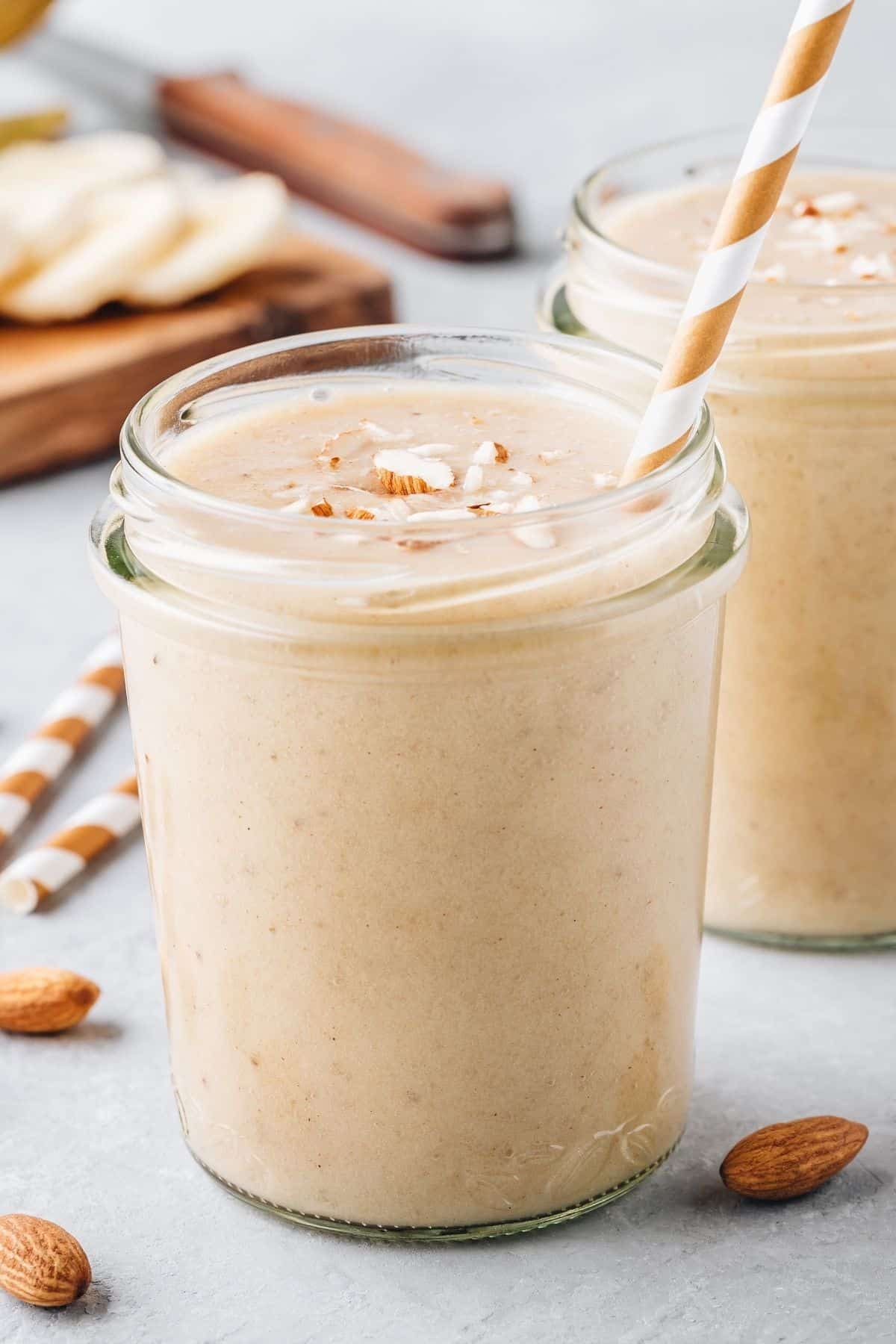 two jars of almond butter paleo smoothies with a straw.