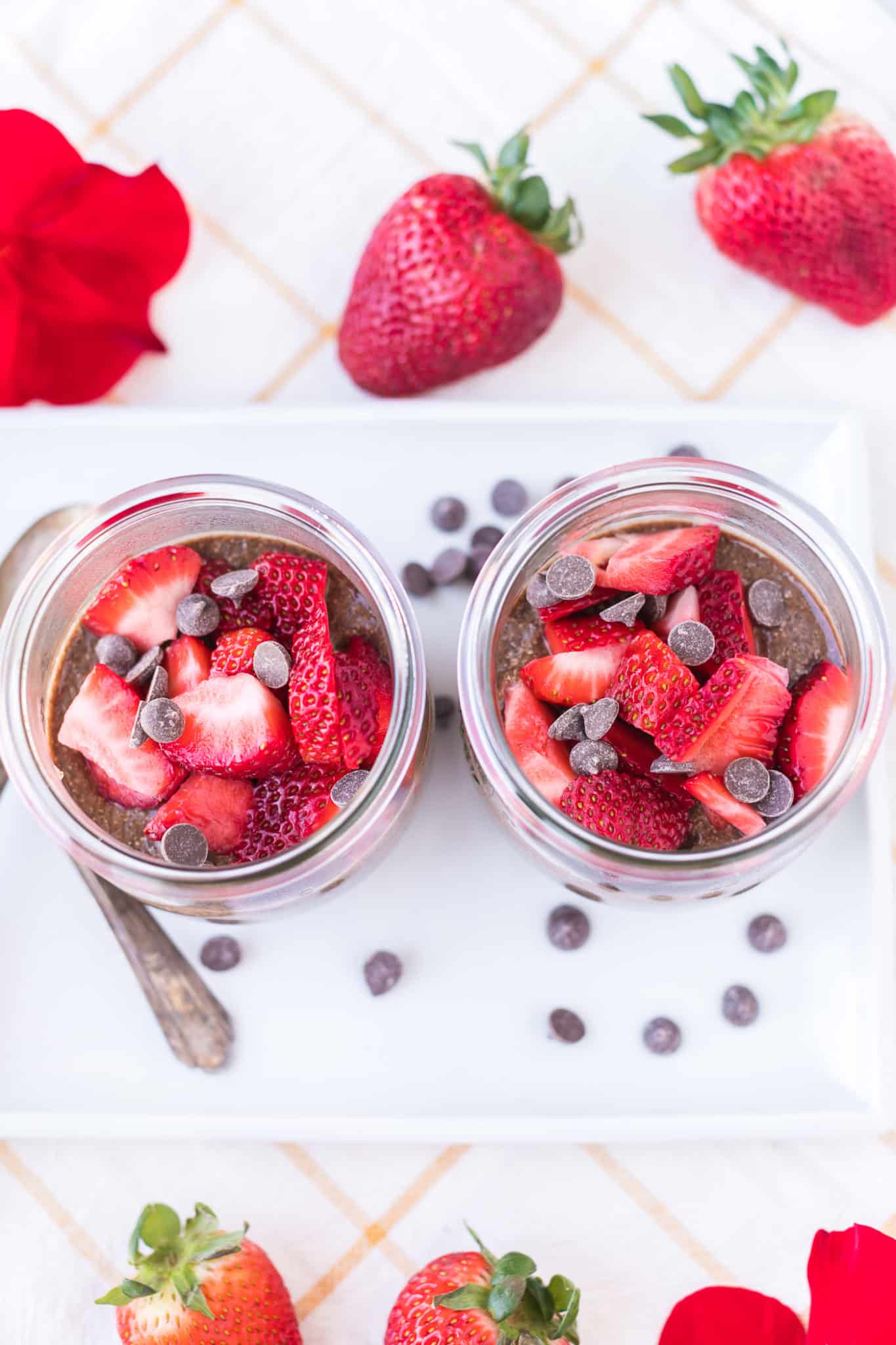 two jars of chocolate chia pudding topped with fresh strawberries